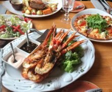 Enjoy a sumptuous seafood meal with lobster, pizza, and salad in a cozy Icelandic restaurant setting.